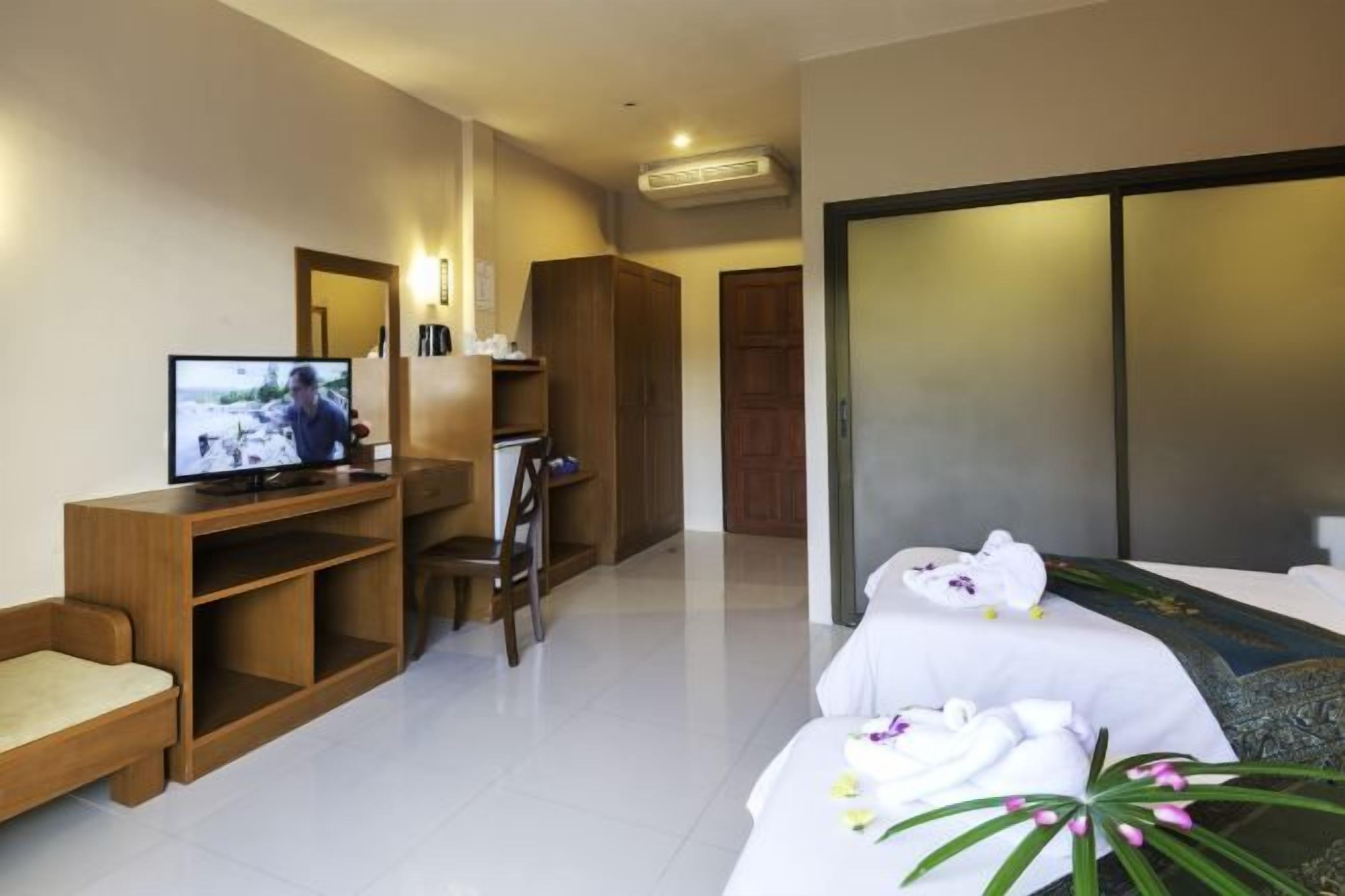 Quarto de hotel com cama, televisão, escrivaninha e cadeira.