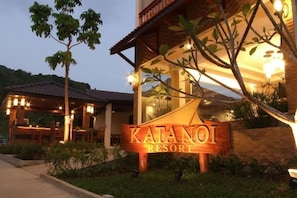 A sign for Katani Resort with a well-lit entrance and a covered outdoor seating area.