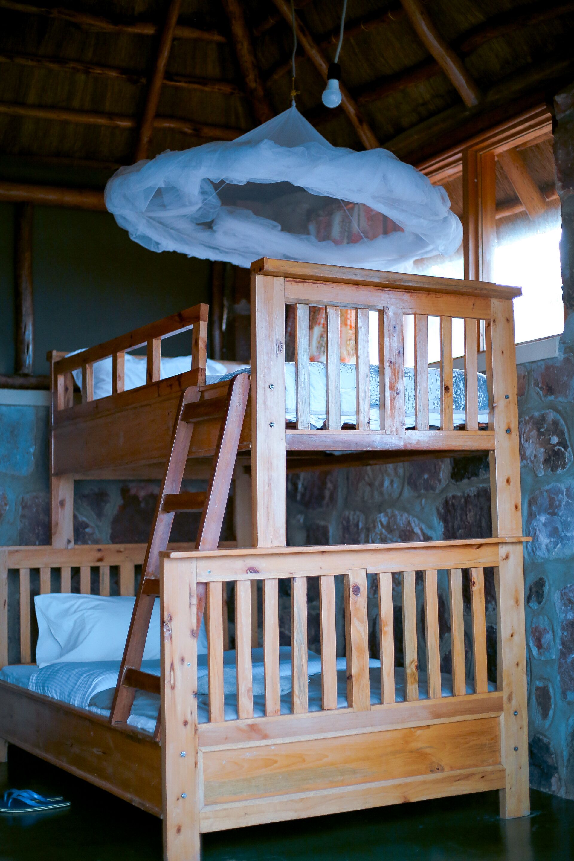 Una litera con escalera, una lámpara colgante y una pared de piedra.