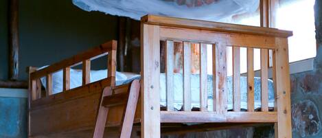Una litera con escalera, una lámpara colgante y una pared de piedra.
