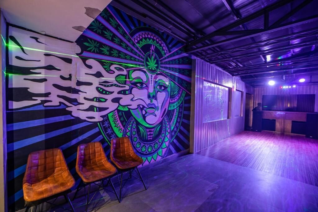 Une pièce décorée d’une fresque murale, dotée d’un plancher en bois et de deux chaises en bois.