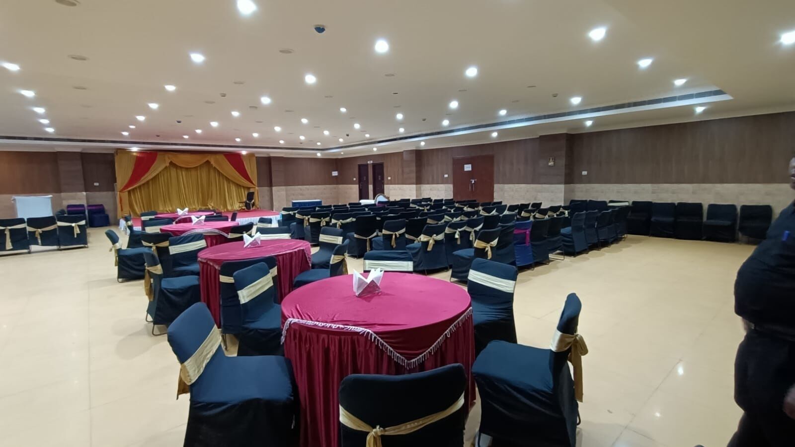 A conference room with round tables, chairs, and a stage.