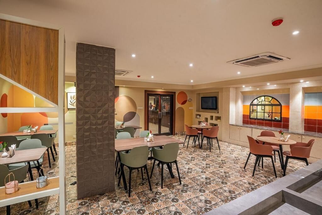 Un restaurante con varias mesas y sillas, un suelo con diseño y una decoración de estilo moderno.
