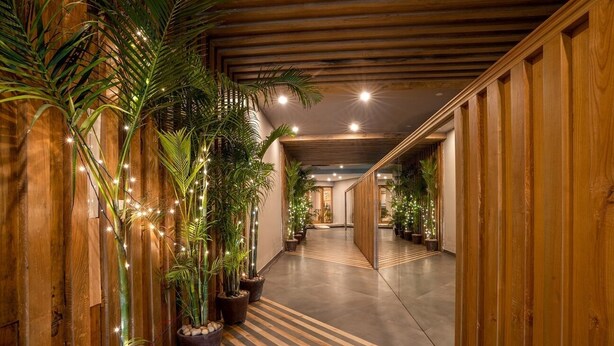 A hallway with wooden paneling, potted plants, and a striped floor. - The Presidency Hotel In Bhubaneswar (Bhubaneshwar)