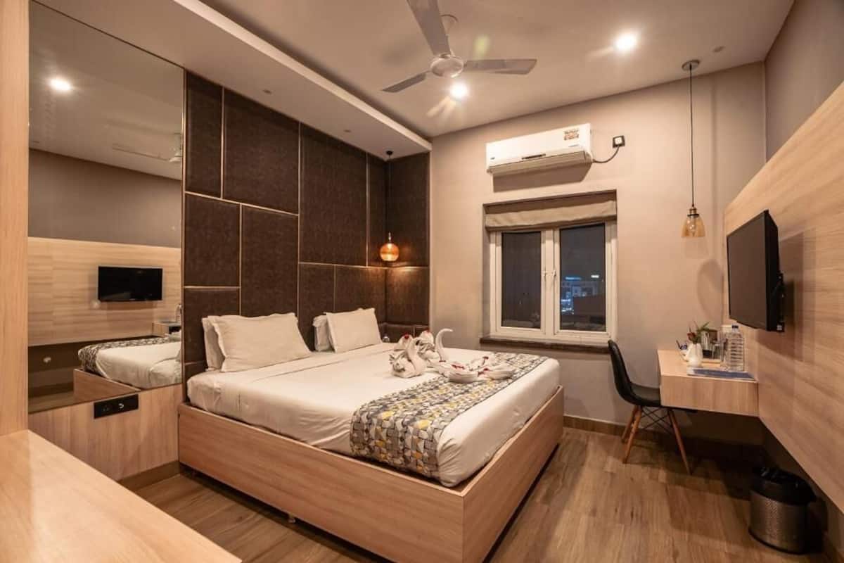 Une chambre moderne avec un grand lit, un bureau, une télévision et une fenêtre.