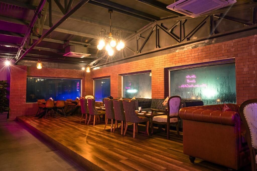 A cozy restaurant with brick walls, wooden flooring, and a mix of leather and fabric seating.