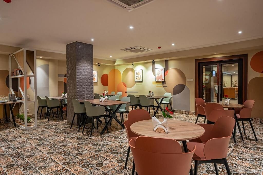 A restaurant with round tables and chairs, a tiled floor, and a wall with abstract art.