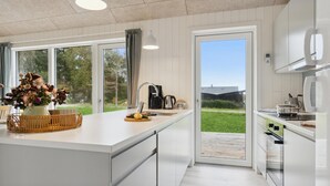 Ett modernt kök med stora fönster, en kaffebryggare och utsikt över omgivningarna.