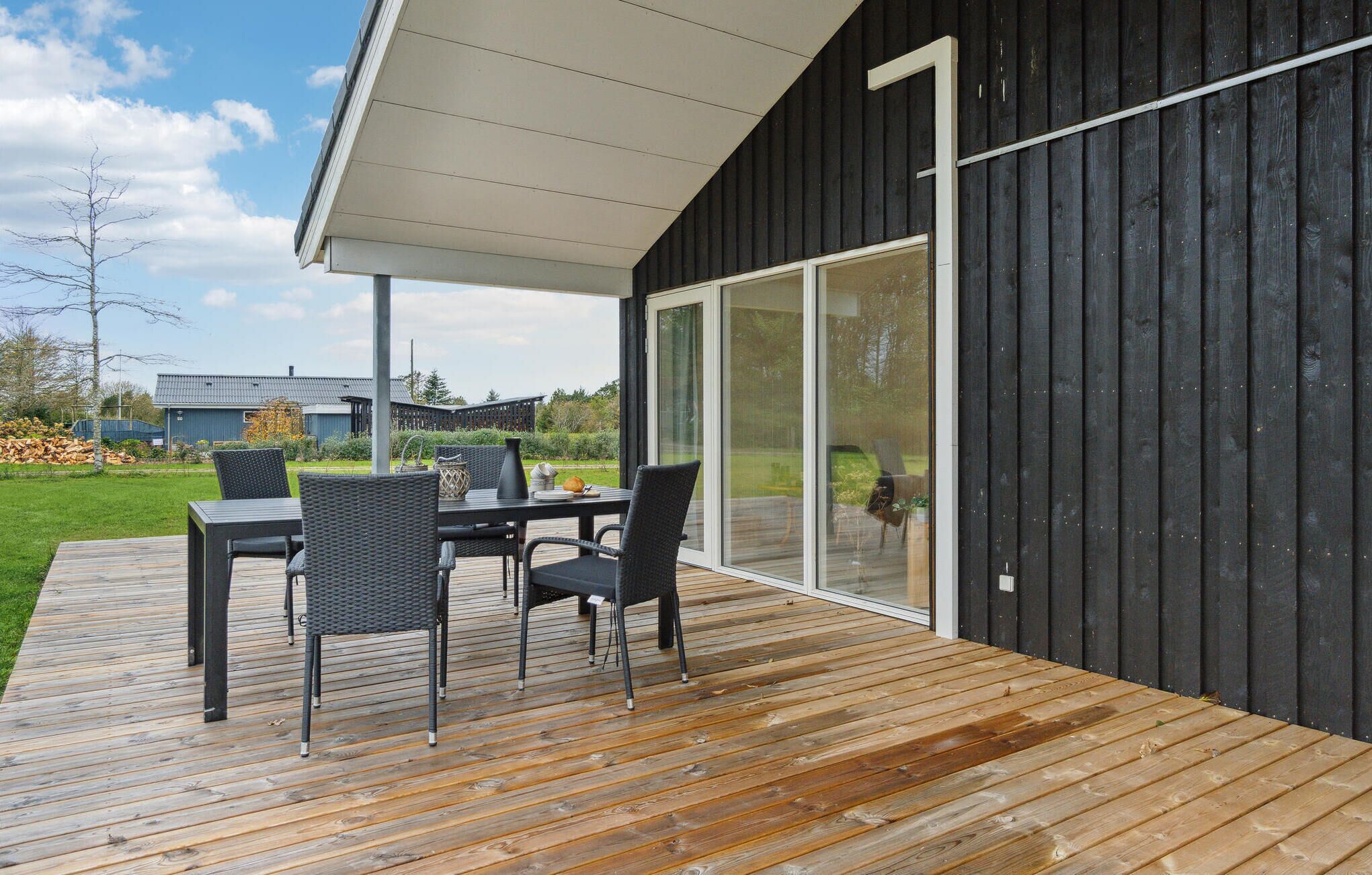 Eine Terrasse mit Gartenmöbeln und einer Schiebetür, die zu einem überdachten Patio führt.