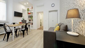Een moderne woonkamer met een eethoek, een bank, een lamp en een televisie.