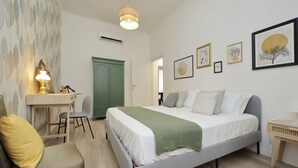 Een slaapkamer met een bed, een bureau, een stoel en een lamp.