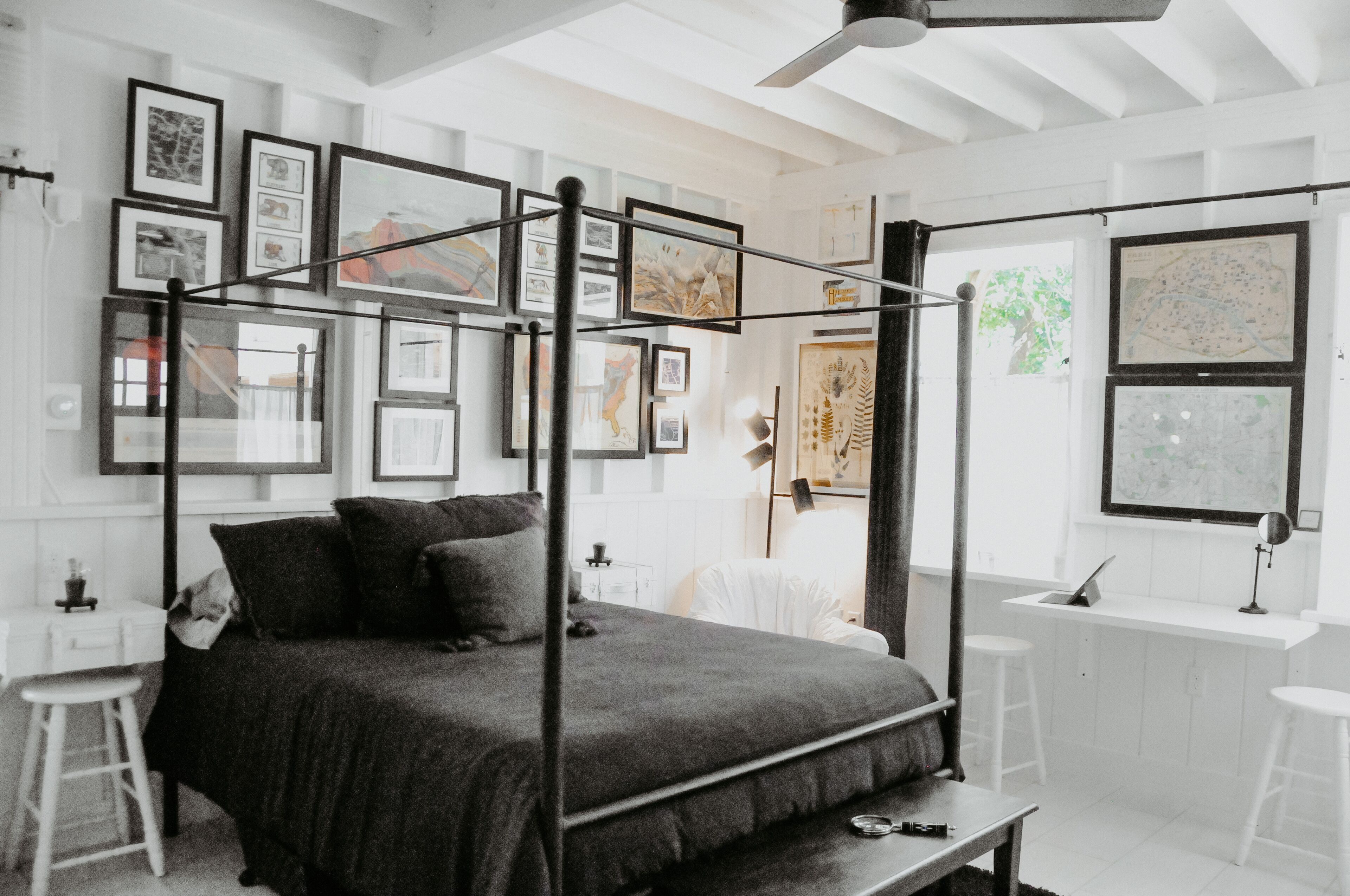 Une chambre à coucher moderne avec un lit à baldaquin, un bureau avec une chaise et une fenêtre donnant sur la ville.