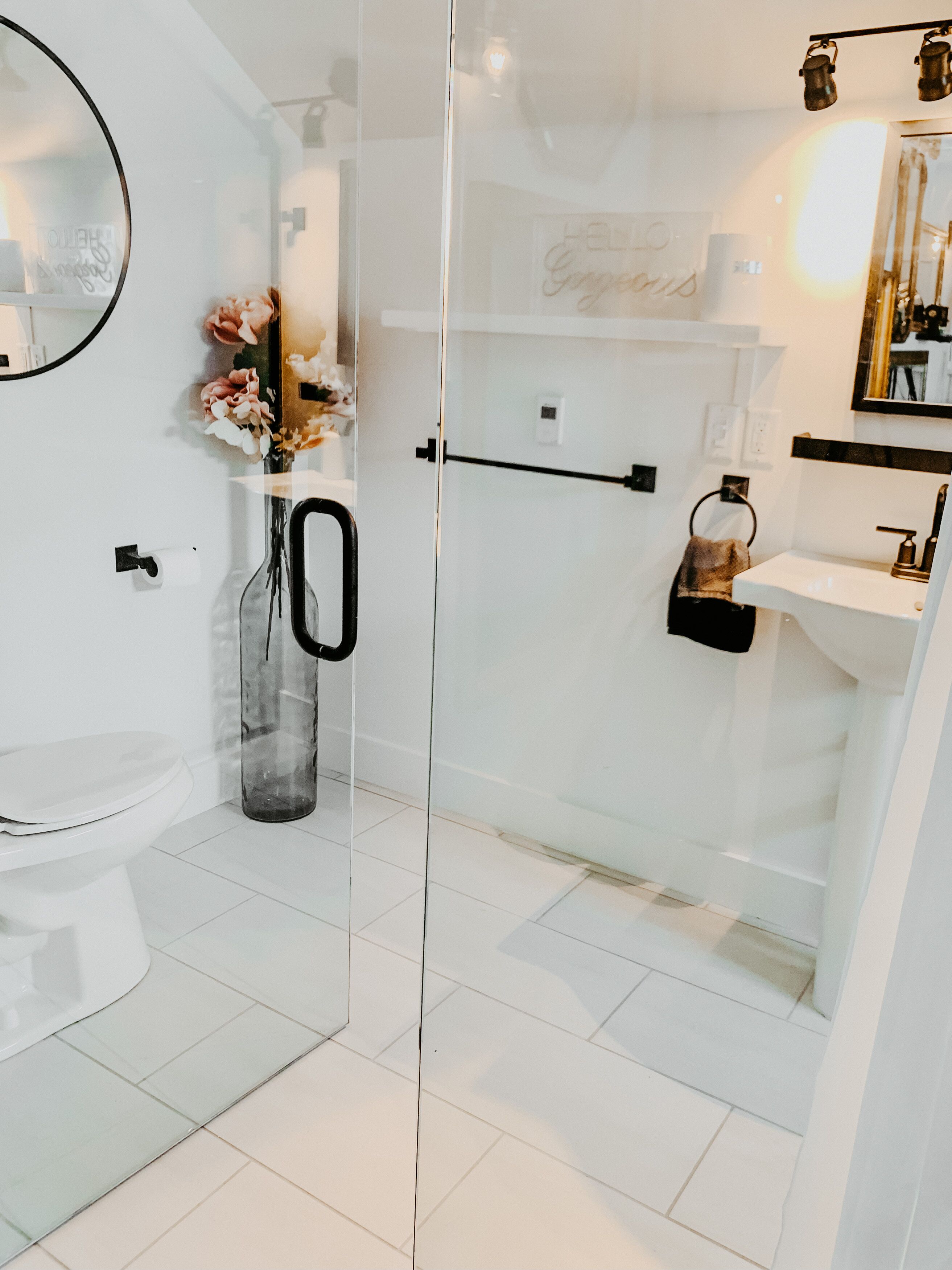 Une salle de bain moderne avec une douche à parois de verre, des toilettes, un lavabo et un miroir.