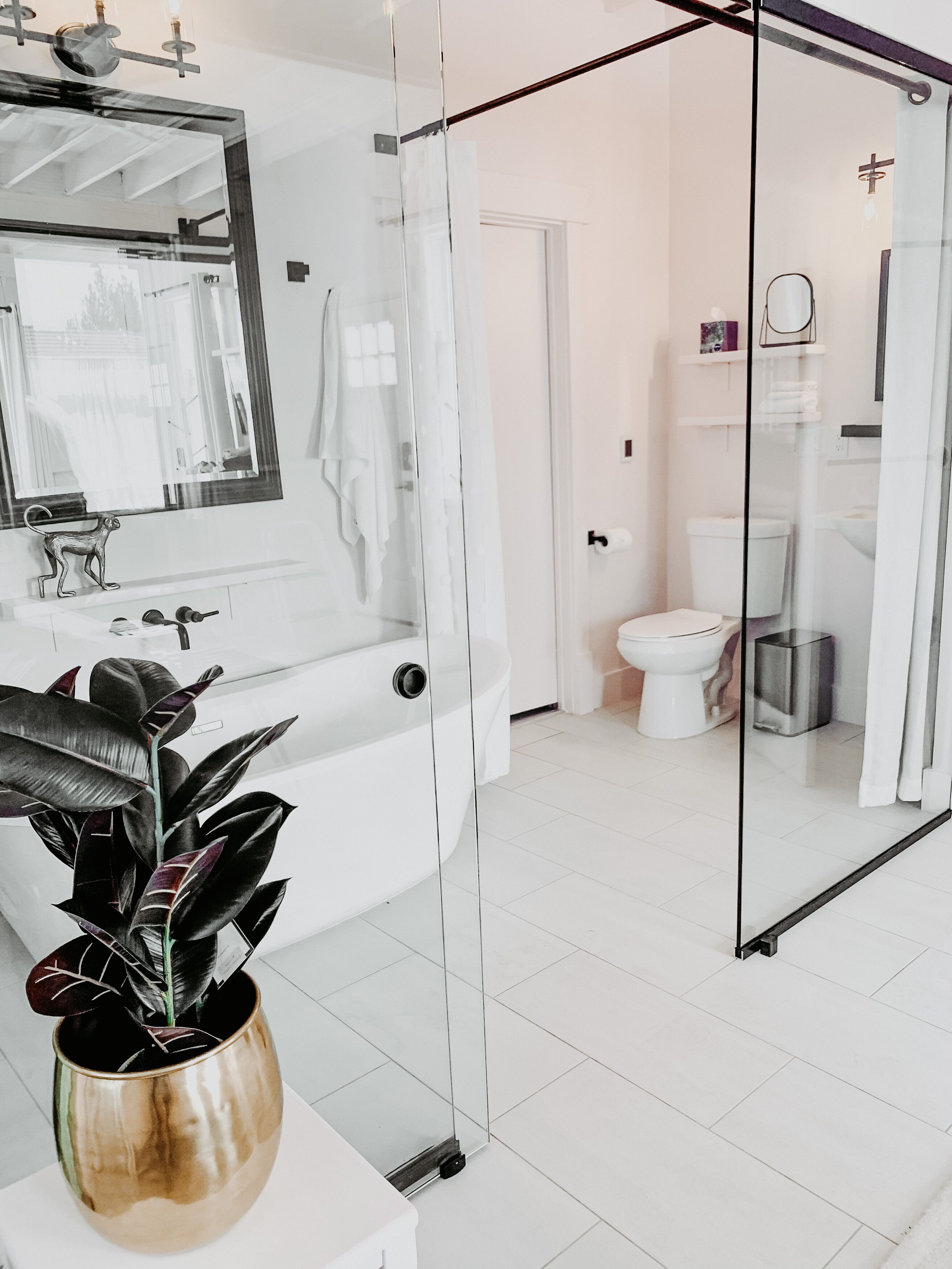 Une salle de bain moderne avec une douche à parois de verre, une baignoire blanche et un grand miroir au-dessus du lavabo.