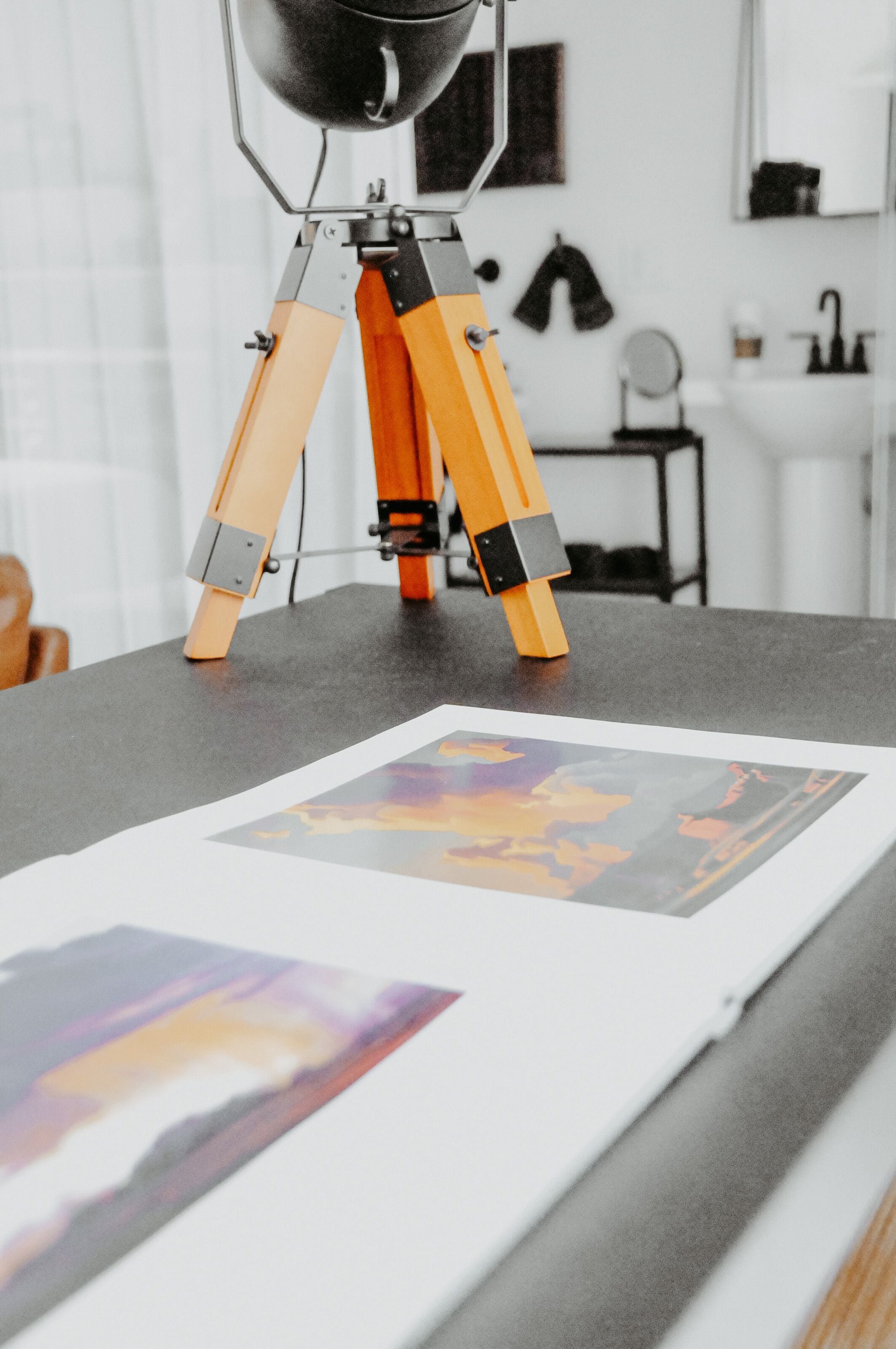 Un appareil photo fixé sur un trépied, posé sur une table, avec une photographie imprimée à proximité.