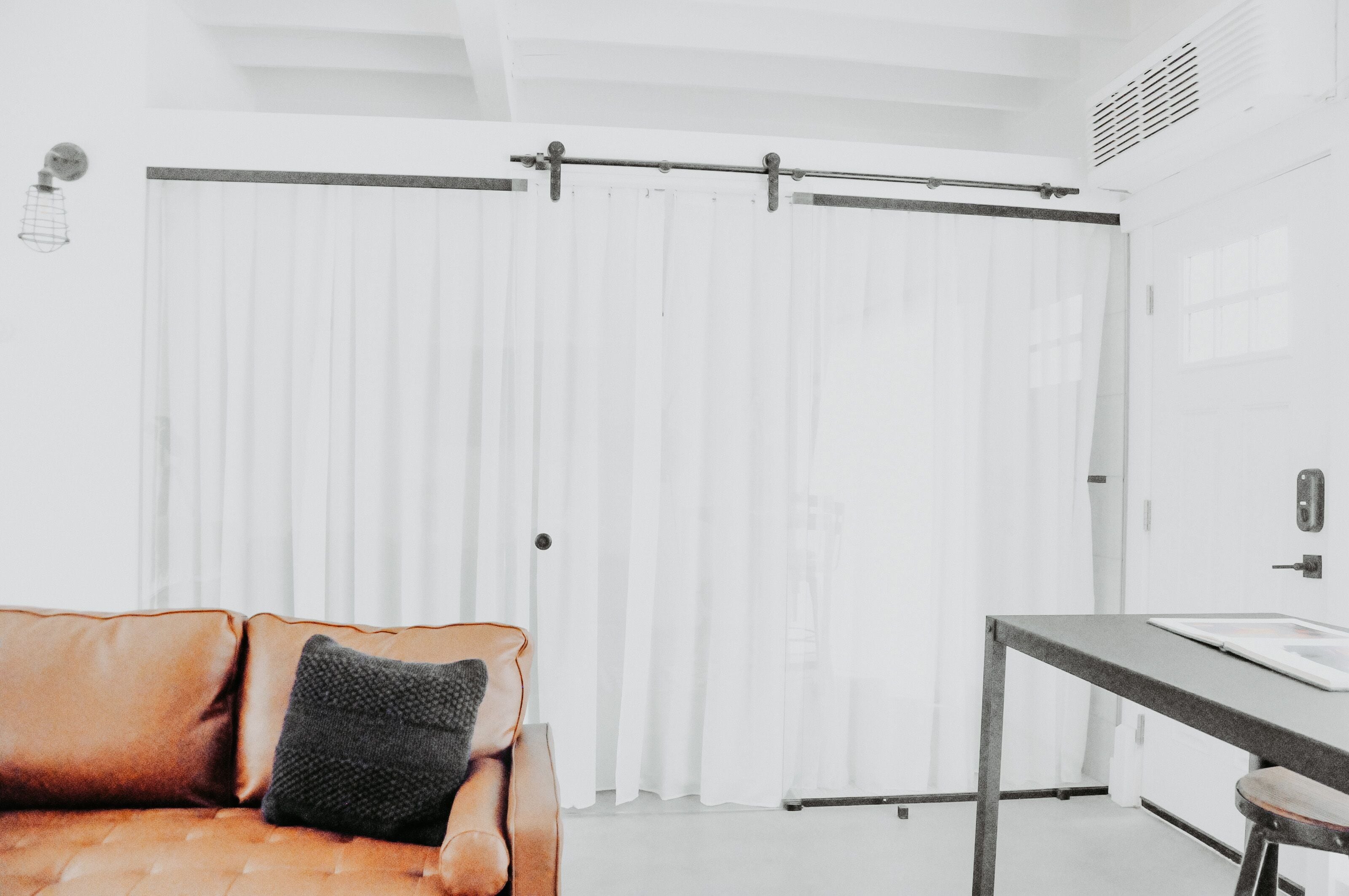 A modern room with a sliding door, a leather sofa, a small table, and a bench.