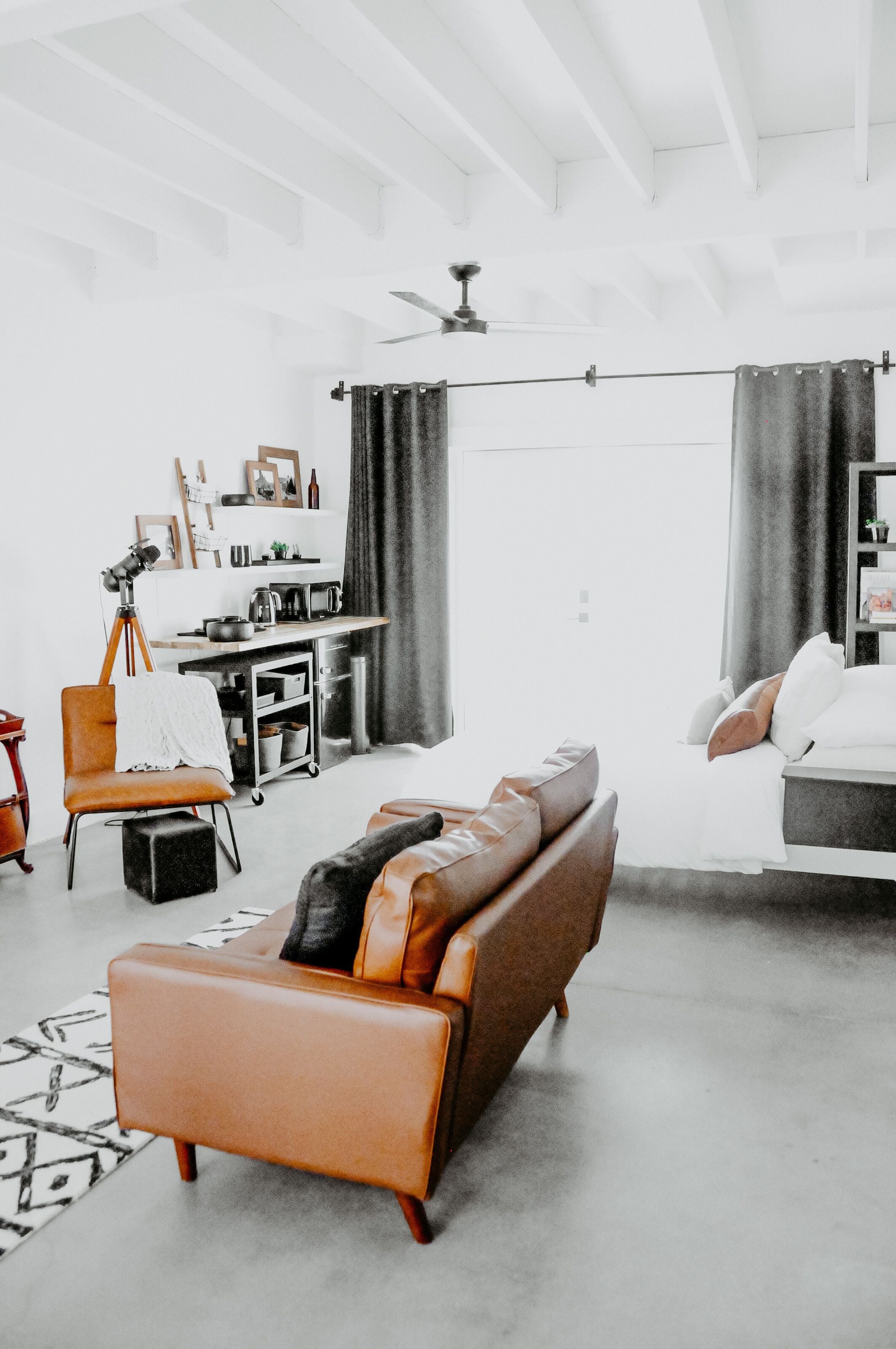 A modern living room with a sofa, a chair, a small table, and a kitchen area in the background.