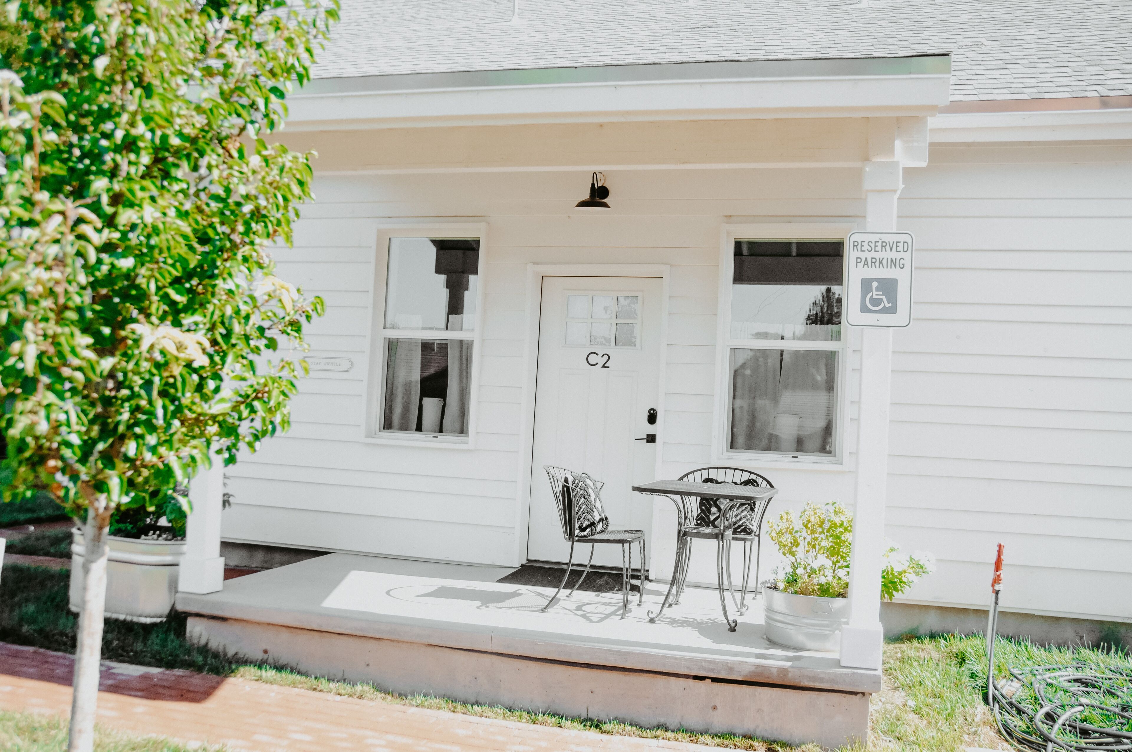 Une maison blanche avec une porte portant l’inscription « C2 » et un panneau indiquant « PLACE DE STATIONNEMENT RÉSERVÉE ».