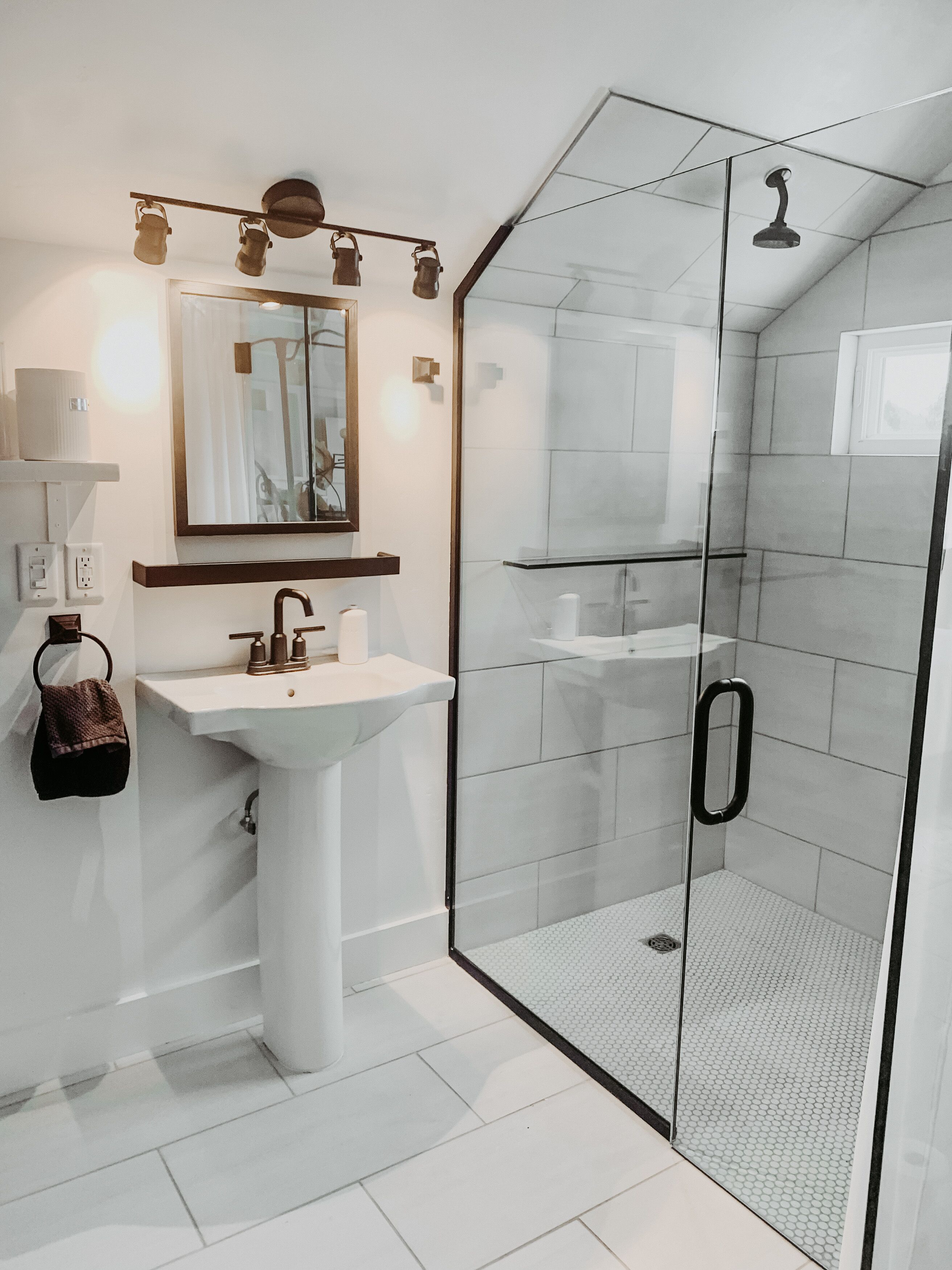 Un bagno moderno con doccia vetrata, lavandino bianco e specchio soprastante.