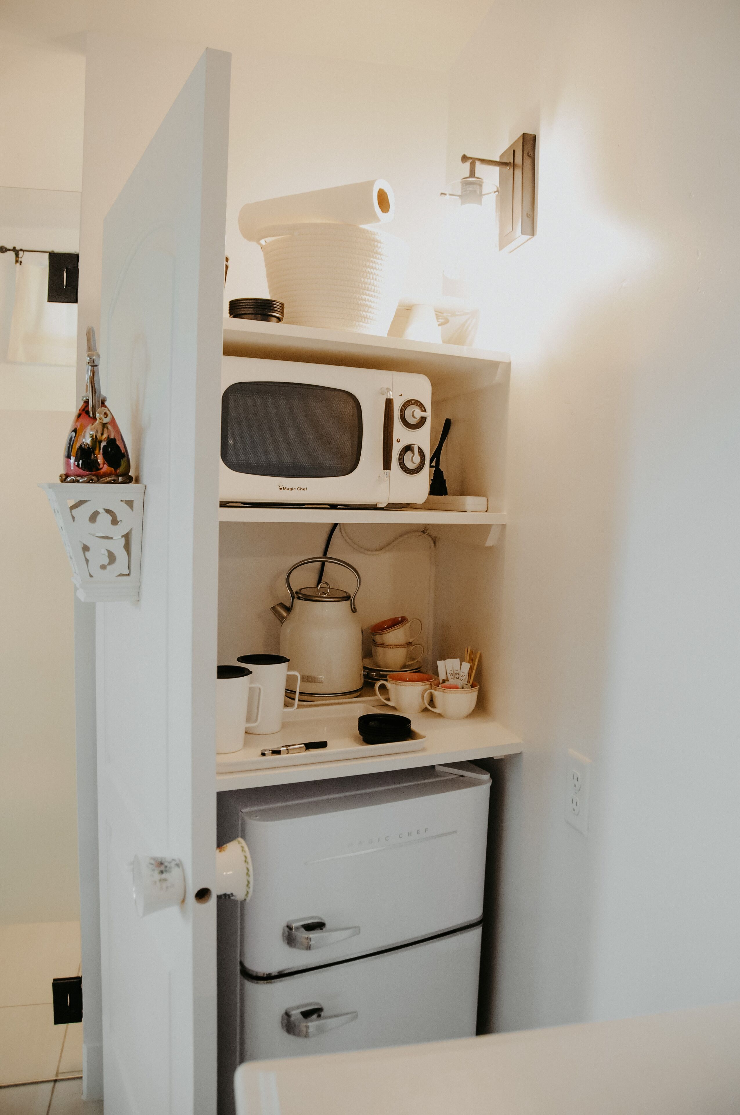 Una cocina compacta equipada con microondas, hervidor y cajones para guardar objetos.