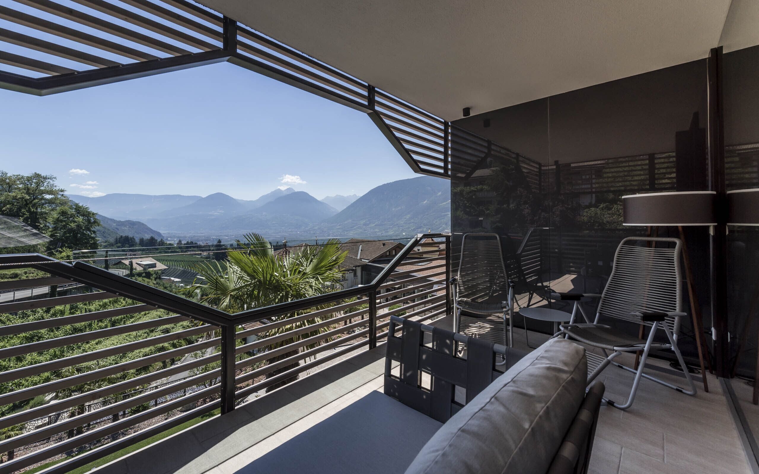 Ein Balkon mit Blick auf Berge, einer Couch und zwei Stühlen.