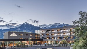 Un hotel moderno con numerosi balconi e uno sfondo montuoso.