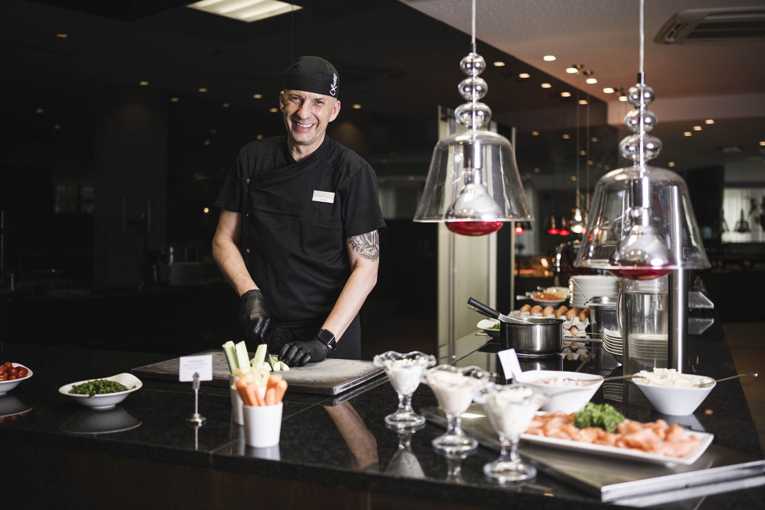 Un buffet proposant une variété de plats et un serveur vêtu d’un uniforme noir.