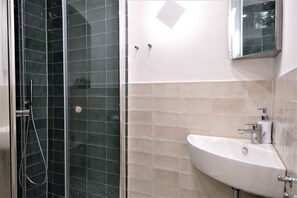 A bathroom with a glass-enclosed shower, a white sink, and a mirror above the sink.