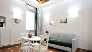 Un espace de vie compact comprenant un coin repas, un canapé et des œuvres d’art accrochées aux murs.