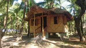 A thatched-roof hut with a simple, open design, surrounded by palm trees. - Sablayan Paraiso Beach Resort (Sablayan)