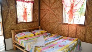 A single bed with colorful bedding, a wooden headboard, and a window with a floral curtain. - Sablayan Paraiso Beach Resort (Sablayan)