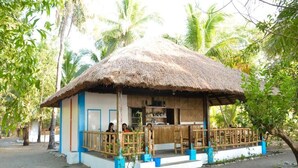 A thatched-roof hut with a wooden porch and a small bar area. - Sablayan Paraiso Beach Resort (Sablayan)