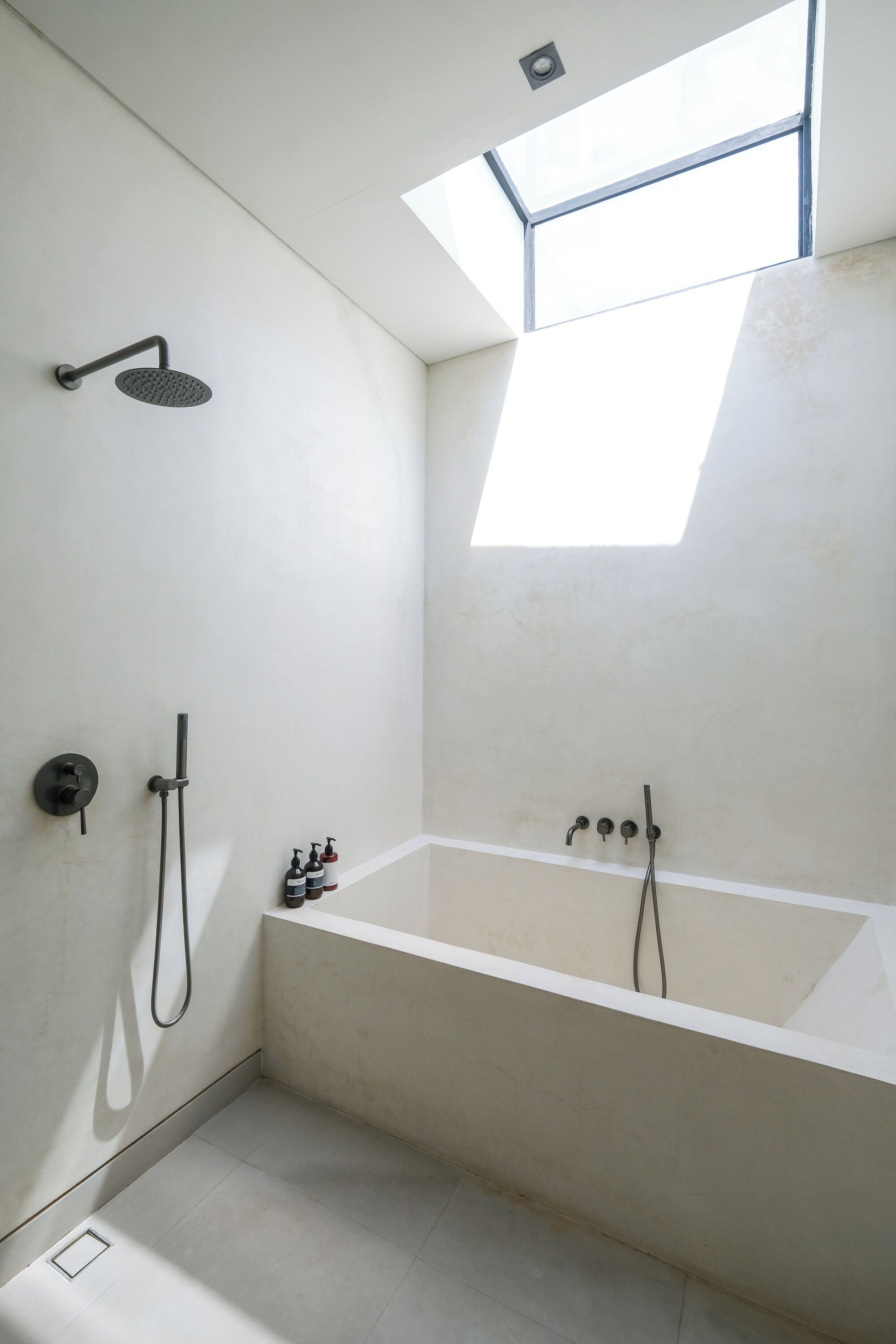 A modern bathroom with a skylight, a freestanding bathtub, and a showerhead.