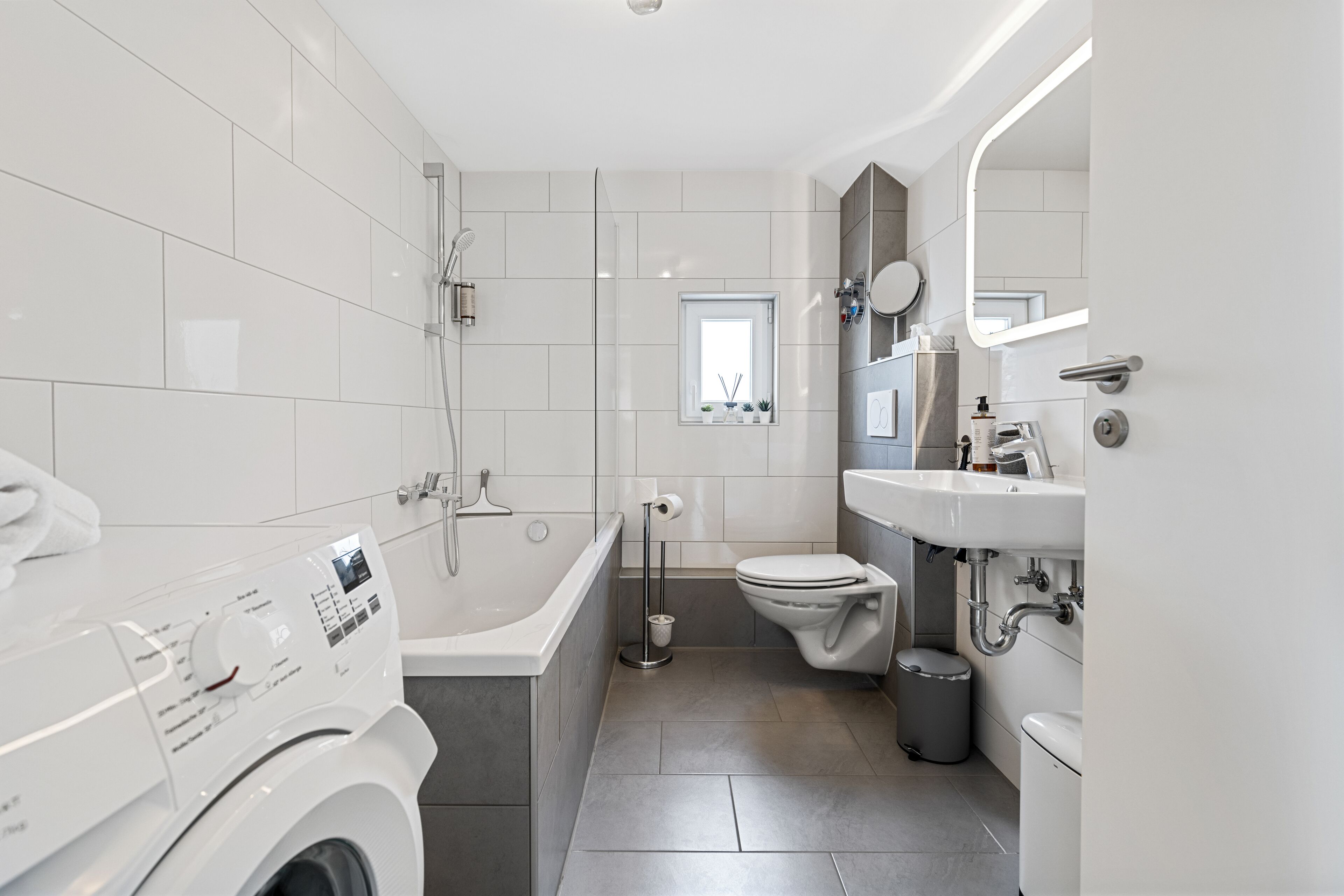 Un baño moderno con lavadora, bañera, inodoro y lavamanos.