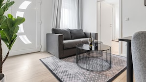 A modern living room with a grey sofa, a round black coffee table, and a patterned rug. - BRIGHT Herzogenaurach Zentrum (Herzogenaurach)