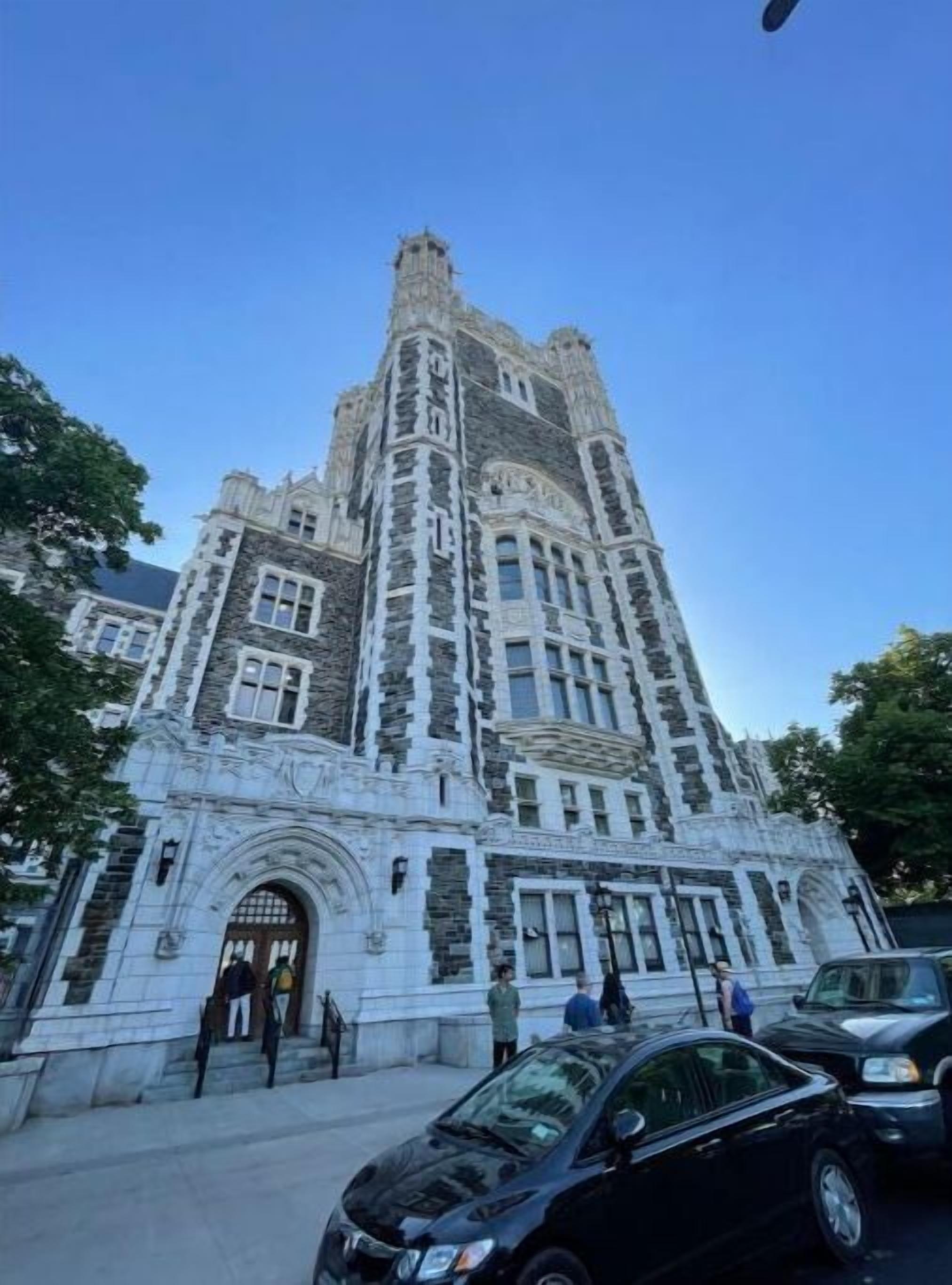 Un edificio histórico con una torre alta, ventanas grandes y una entrada ornamentada.