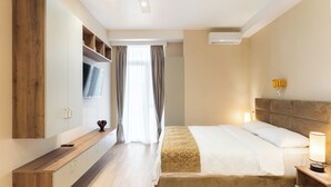 A modern bedroom with a bed, bedside table, TV, and built-in wardrobe. - Sky By The River (Tbilisi)