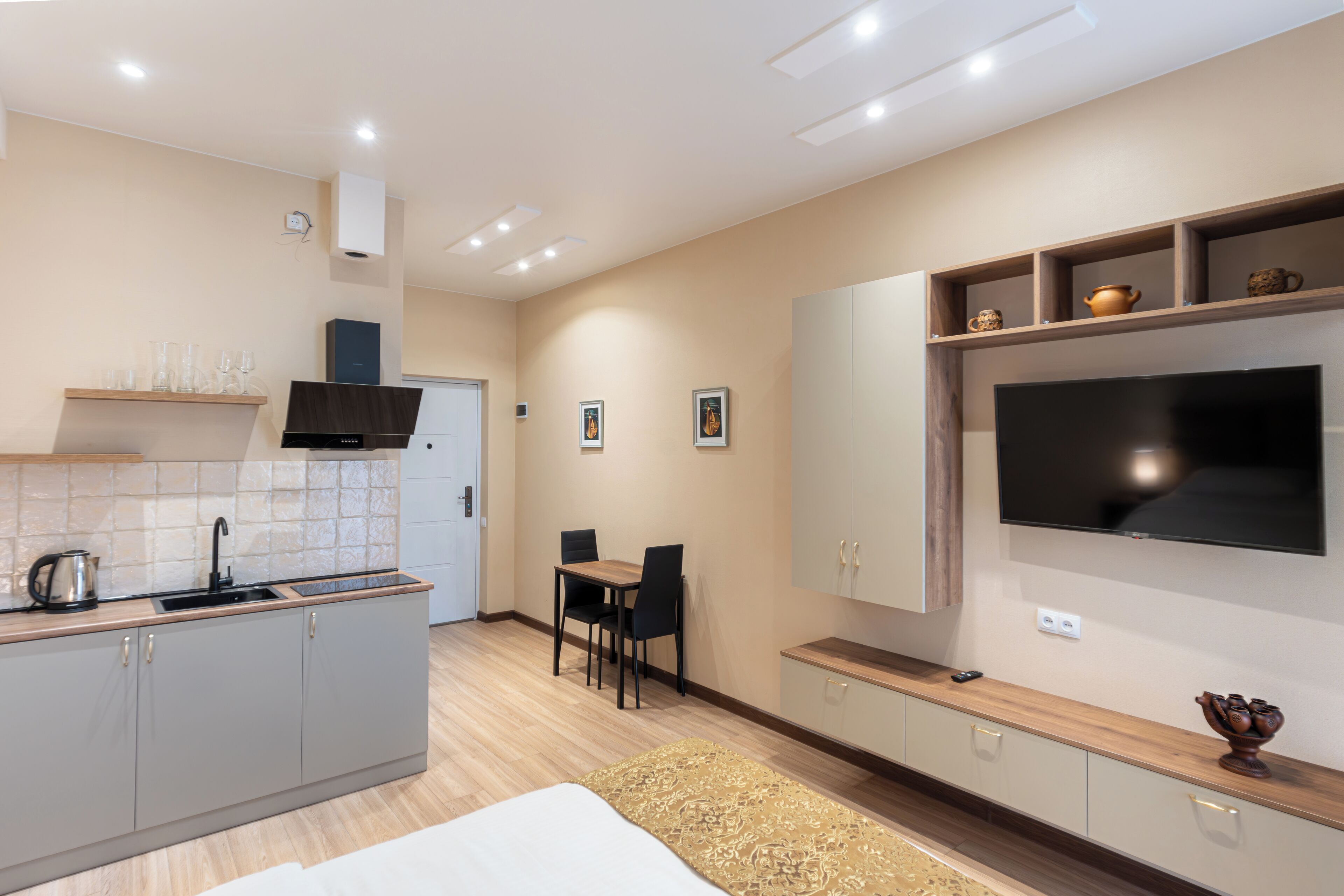 A modern kitchen with a dining area, a flat-screen TV, and a built-in oven.