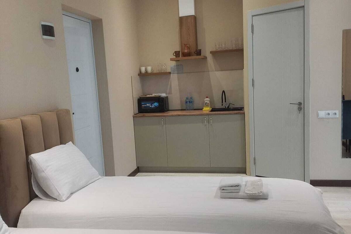 Ett hotellrum med två sängar, ett litet kök och ett badrum.