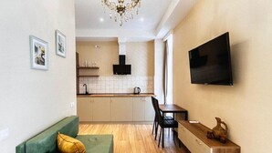 A modern living room with a green sofa, a wooden coffee table, and a TV mounted on the wall. - Sky By The River (Tbilisi)