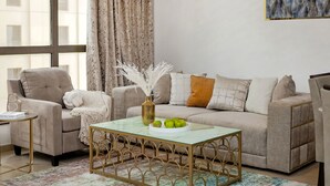 A living room with a beige sofa, a glass coffee table, and a patterned rug. - 2BR apartment 2 minutes to beach Amwaj 4 (Dubai)