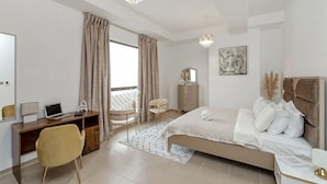 A modern bedroom with a bed, desk, and chair. - 2BR apartment 2 minutes to beach Amwaj 4 (Dubai)