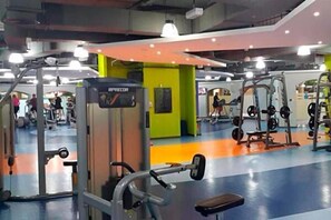 A gym with various exercise machines, a mirror, and a colorful floor. - 2BR apartment 2 minutes to beach Amwaj 4 (Dubai)