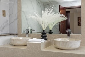 A bathroom with two marble sinks, a mirror, and a decorative plant in a black vase. - 2BR apartment 2 minutes to beach Amwaj 4 (Dubai)