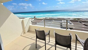 A balcony with a view of the ocean, featuring a railing and several chairs. - Oceanfront white sand beach condo  (Cancun)