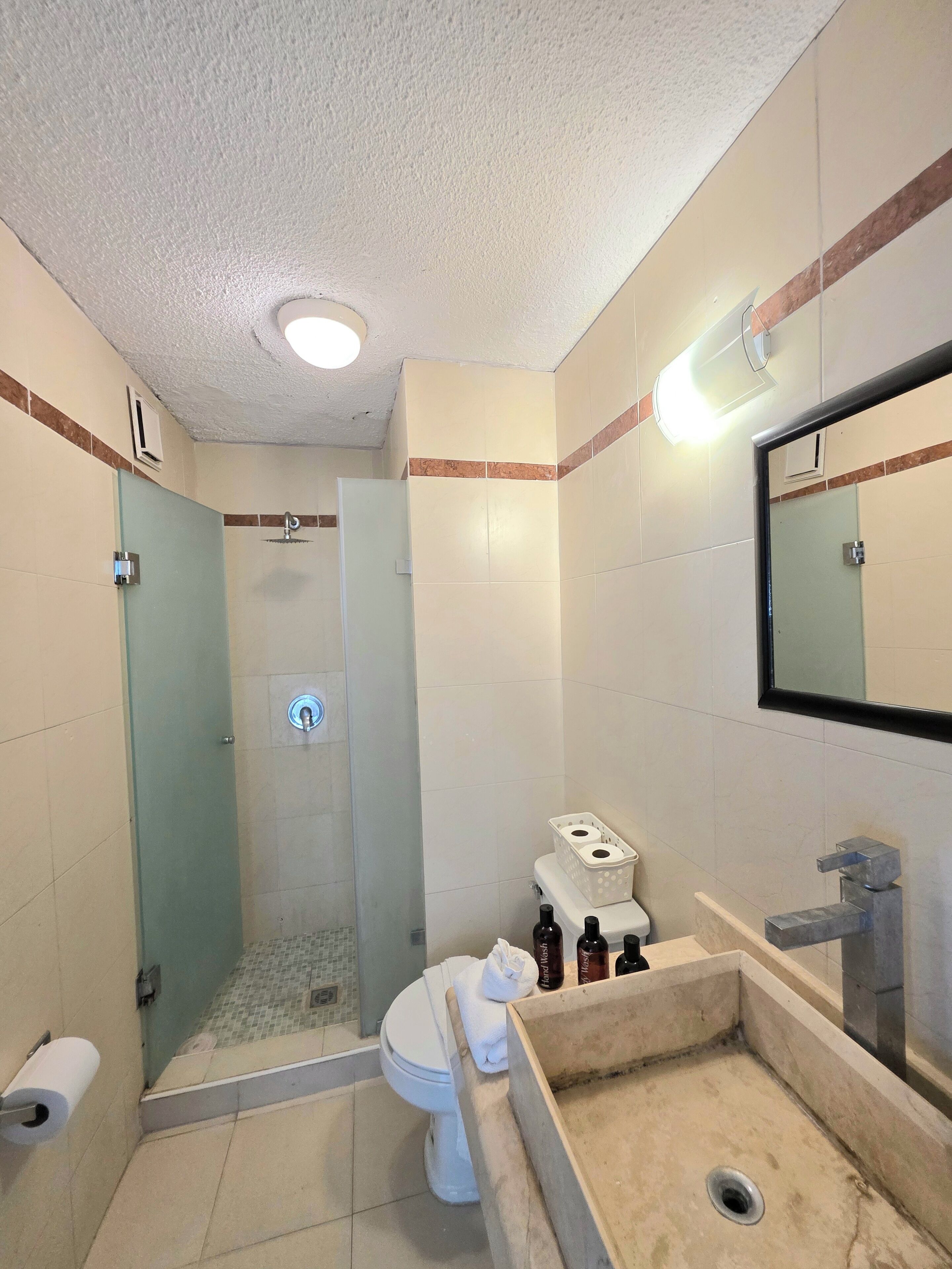 Une salle de bain moderne avec une douche à parois de verre, des toilettes, un lavabo et un miroir.