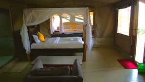 A tent-style room with a bed, a bench, and a small table. - Masai Mara Explore Camp (Narok)