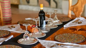 A dining table set with plates, glasses, and cutlery, with a bottle of wine in the center. - Masai Mara Explore Camp (Narok)