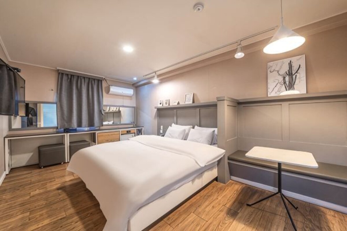 A modern hotel room with a large bed, a desk, and a dining table.