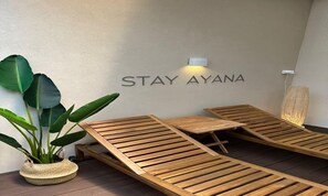 Una habitación con sillones de madera y un letrero en la pared que dice "STAY AYANA".